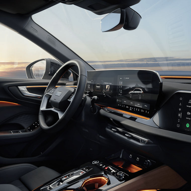 Interior of an Audi car at sunset with a digital dashboard.